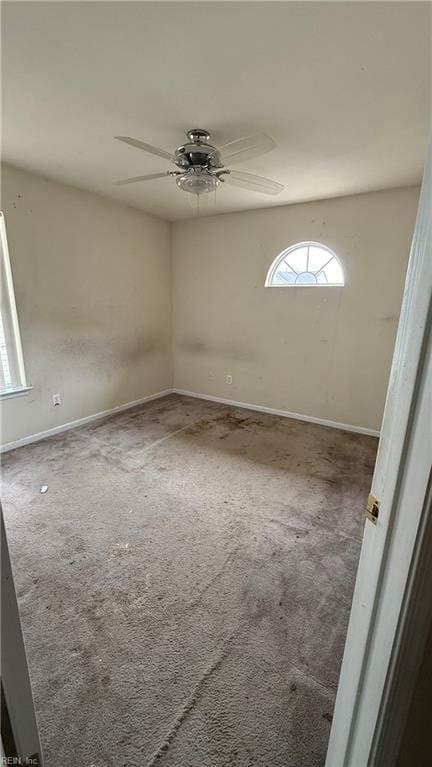 spare room with ceiling fan, carpet floors, and baseboards