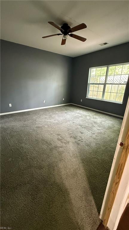 carpeted empty room featuring visible vents, a ceiling fan, and baseboards
