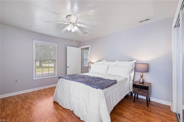 bedroom featuring light wood finished floors, visible vents, ceiling fan, and baseboards