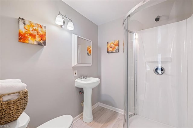 full bath with toilet, a stall shower, and baseboards