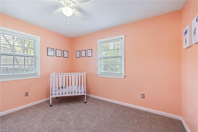 carpeted bedroom featuring ceiling fan, a crib, and baseboards