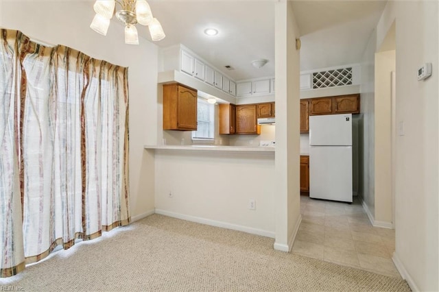 kitchen with freestanding refrigerator, light countertops, brown cabinets, light colored carpet, and baseboards