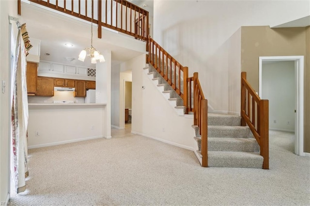 stairs featuring carpet floors, a chandelier, baseboards, and a towering ceiling