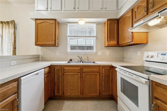 kitchen featuring white appliances, under cabinet range hood, a sink, and brown cabinetry