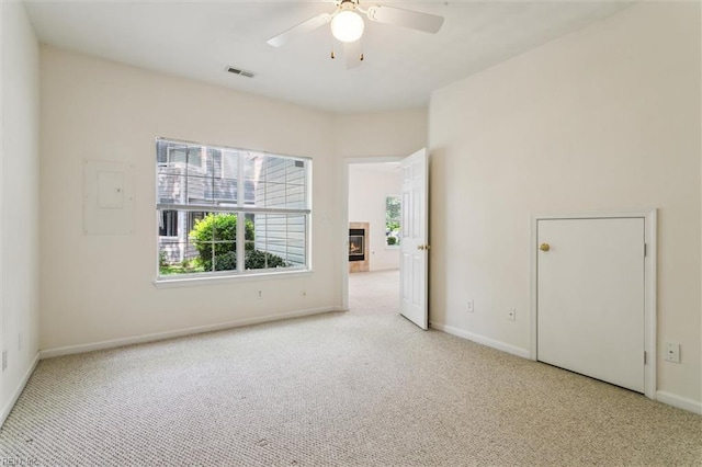 spare room featuring carpet floors, plenty of natural light, baseboards, and a ceiling fan