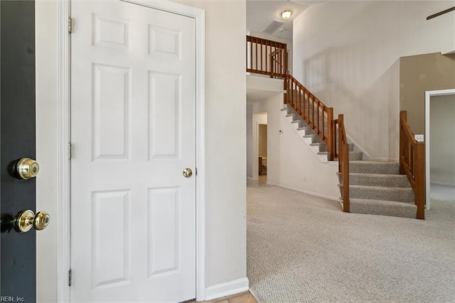 carpeted foyer entrance featuring stairs and baseboards