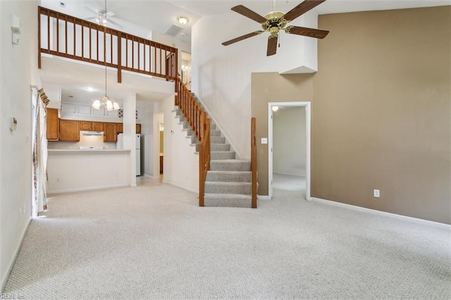 unfurnished living room featuring ceiling fan, high vaulted ceiling, light carpet, stairs, and baseboards