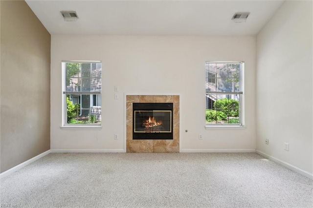 unfurnished living room featuring carpet flooring, a tiled fireplace, and baseboards