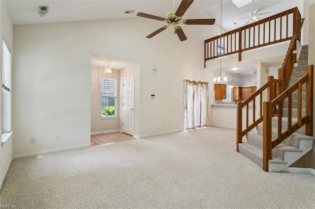 unfurnished living room featuring a ceiling fan, carpet, high vaulted ceiling, stairs, and baseboards