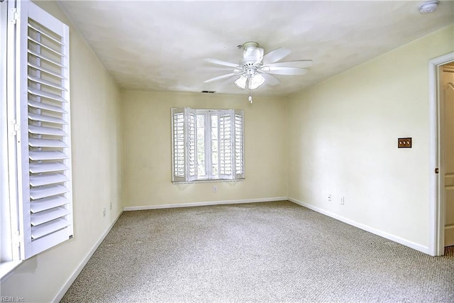 carpeted empty room with visible vents, a ceiling fan, and baseboards