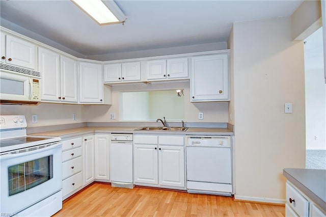 kitchen featuring white cabinets, a sink, light countertops, light wood finished floors, and white appliances
