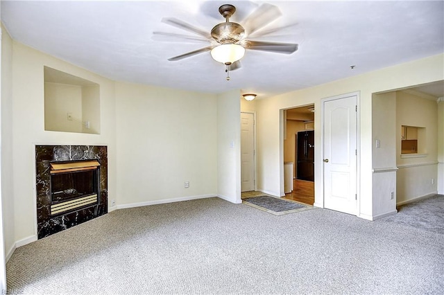 unfurnished living room with a ceiling fan, baseboards, a high end fireplace, and carpet floors