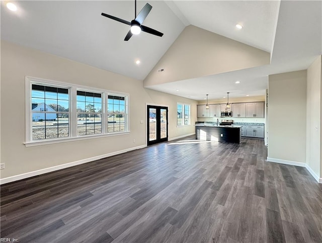 unfurnished living room with dark wood finished floors, recessed lighting, baseboards, high vaulted ceiling, and a ceiling fan
