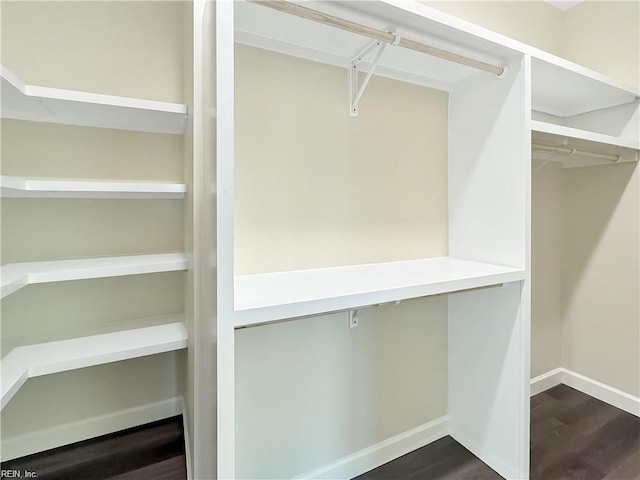walk in closet with dark wood-type flooring