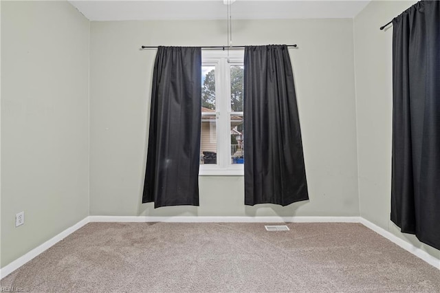 carpeted spare room featuring visible vents and baseboards