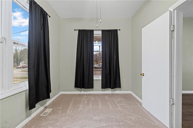 unfurnished room with carpet flooring, visible vents, and baseboards