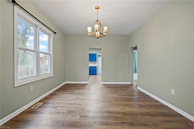 unfurnished dining area featuring visible vents, a notable chandelier, dark wood finished floors, and baseboards
