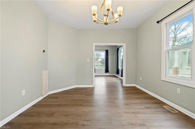 unfurnished dining area with a chandelier, visible vents, wood finished floors, and baseboards