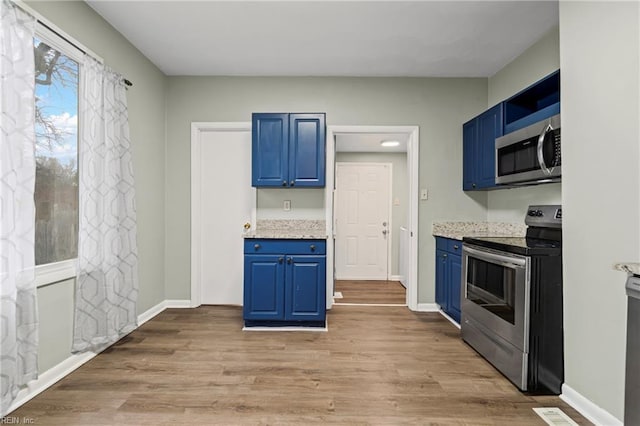 kitchen with light wood-style floors, appliances with stainless steel finishes, and blue cabinetry