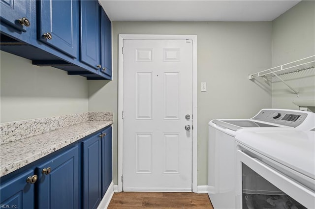 laundry room featuring dark wood-style flooring, baseboards, cabinet space, and washing machine and dryer