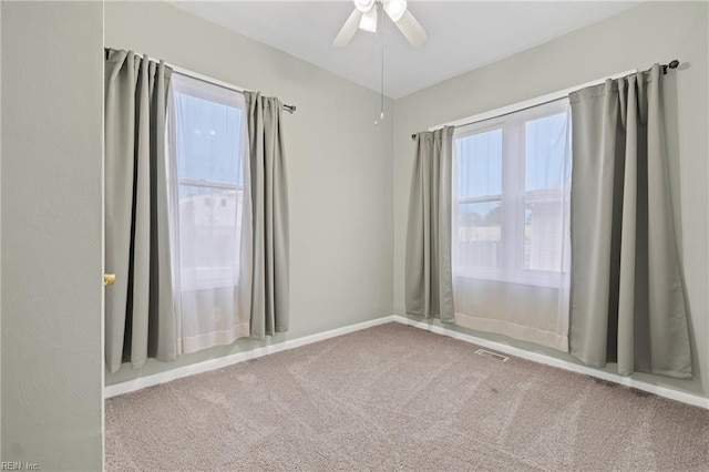 unfurnished room featuring baseboards, visible vents, ceiling fan, and carpet flooring