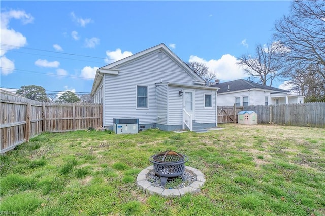 back of property featuring a fire pit, entry steps, a fenced backyard, and a yard