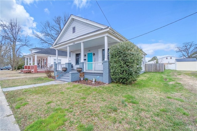 shotgun-style home with a porch, a front lawn, and fence