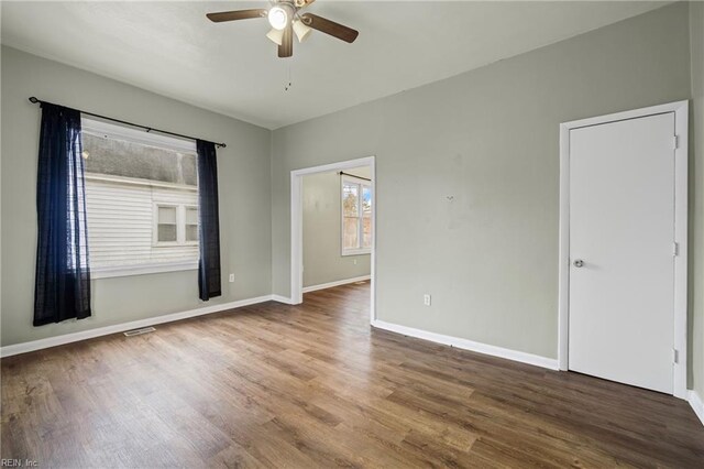 spare room featuring baseboards, visible vents, wood finished floors, and a ceiling fan