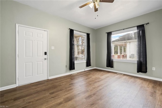 spare room featuring baseboards, visible vents, wood finished floors, and ceiling fan