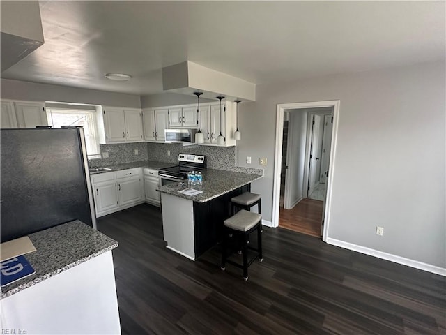 kitchen with white cabinetry, stainless steel appliances, dark wood-style floors, and a peninsula