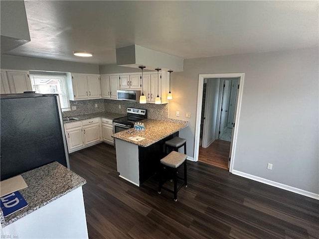 kitchen featuring tasteful backsplash, white cabinets, stainless steel appliances, dark wood-type flooring, and a peninsula