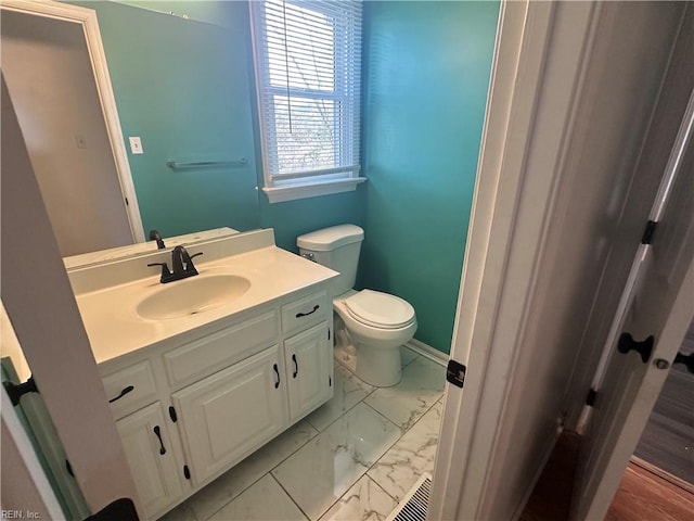 bathroom featuring toilet, marble finish floor, vanity, and baseboards