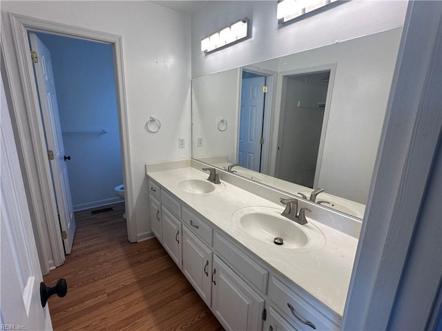 full bath featuring double vanity, wood finished floors, toilet, and a sink