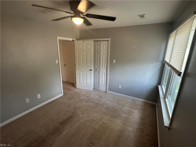 unfurnished bedroom featuring ceiling fan, visible vents, a closet, baseboards, and carpet floors