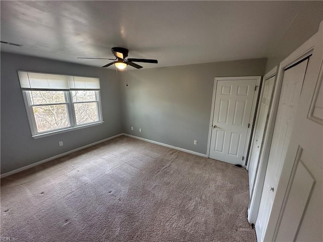 unfurnished bedroom with carpet flooring, ceiling fan, visible vents, baseboards, and multiple closets