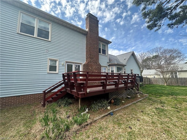rear view of property with a deck, a chimney, fence, central AC, and a lawn