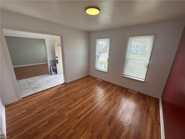 empty room with visible vents, wood finished floors, and baseboards