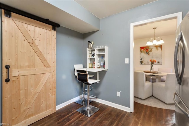 bar featuring baseboards, a barn door, wood finished floors, and freestanding refrigerator