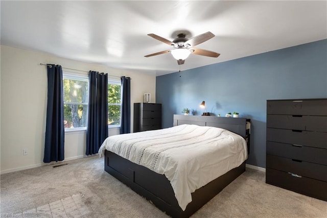 bedroom featuring baseboards, light carpet, a ceiling fan, and visible vents