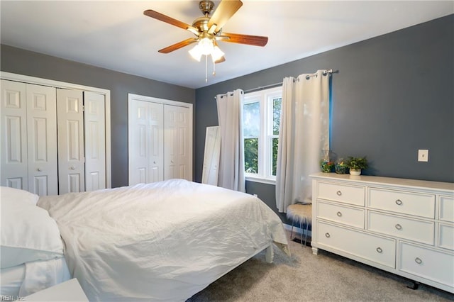 carpeted bedroom with ceiling fan and multiple closets