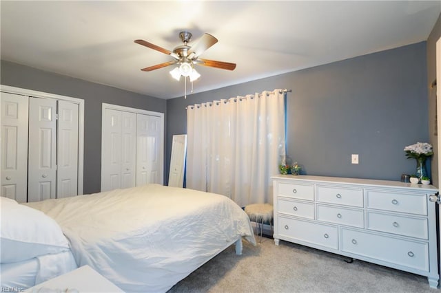 carpeted bedroom with multiple closets and a ceiling fan