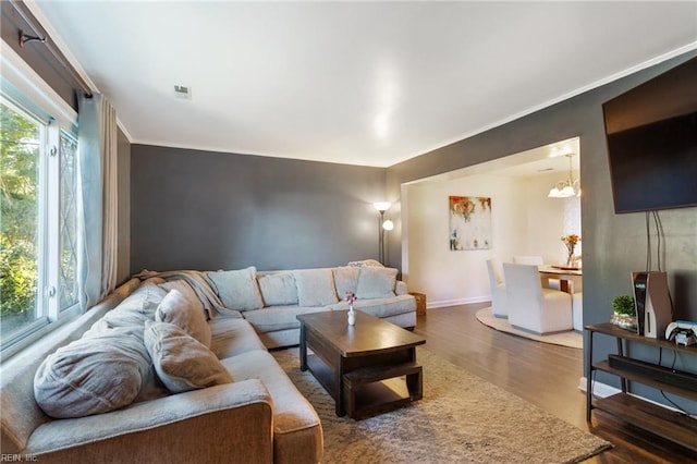 living area with plenty of natural light, baseboards, crown molding, and wood finished floors