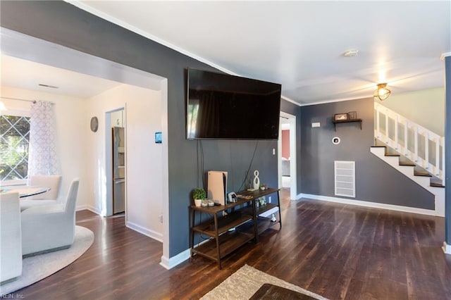living area featuring stairs, baseboards, wood finished floors, visible vents, and ornamental molding