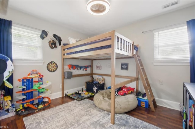 bedroom with wood finished floors, visible vents, and multiple windows