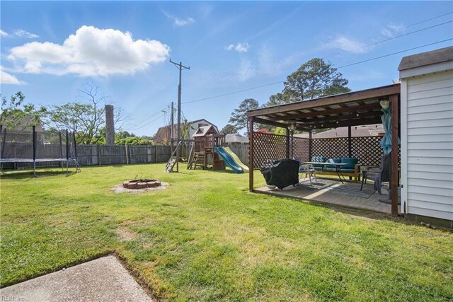 view of yard featuring a trampoline, a fenced backyard, an outdoor living space with a fire pit, a patio area, and a playground
