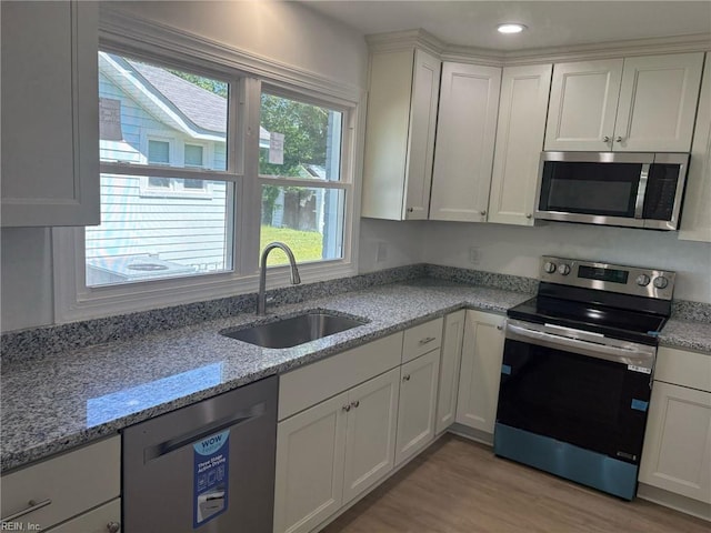 38 W Sherwood Ave, Hampton, VA 23663 - kitchen with white cabinets, a sink, appliances with stainless steel finishes, light wood-type flooring, and light stone countertops