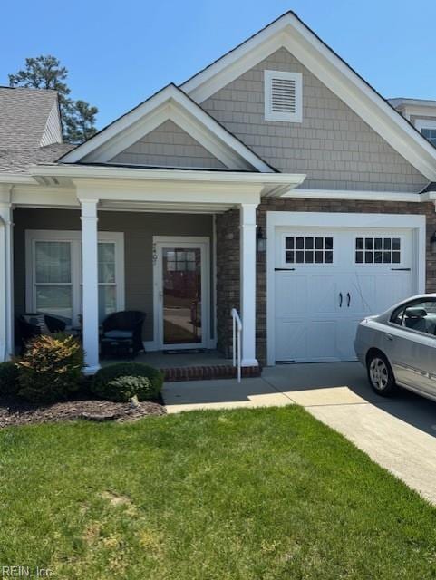 view of front of property featuring covered porch, driveway, a front lawn, an attached garage, and stone siding