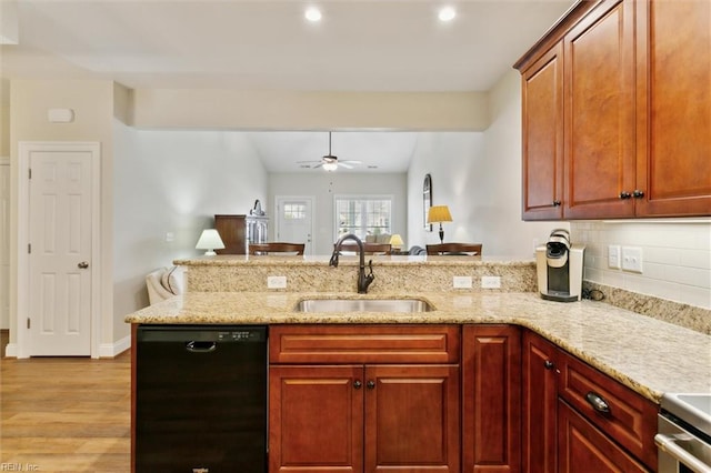 kitchen featuring a sink, light stone counters, a peninsula, light wood-style floors, and black dishwasher