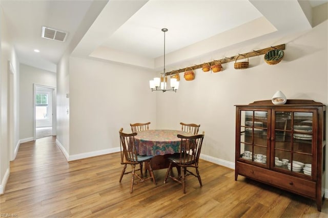 dining space featuring baseboards, a notable chandelier, wood finished floors, and visible vents