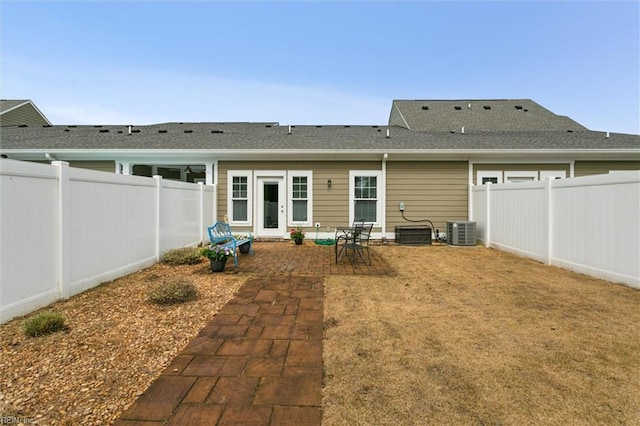 back of property with a fenced backyard, a patio, cooling unit, and roof with shingles
